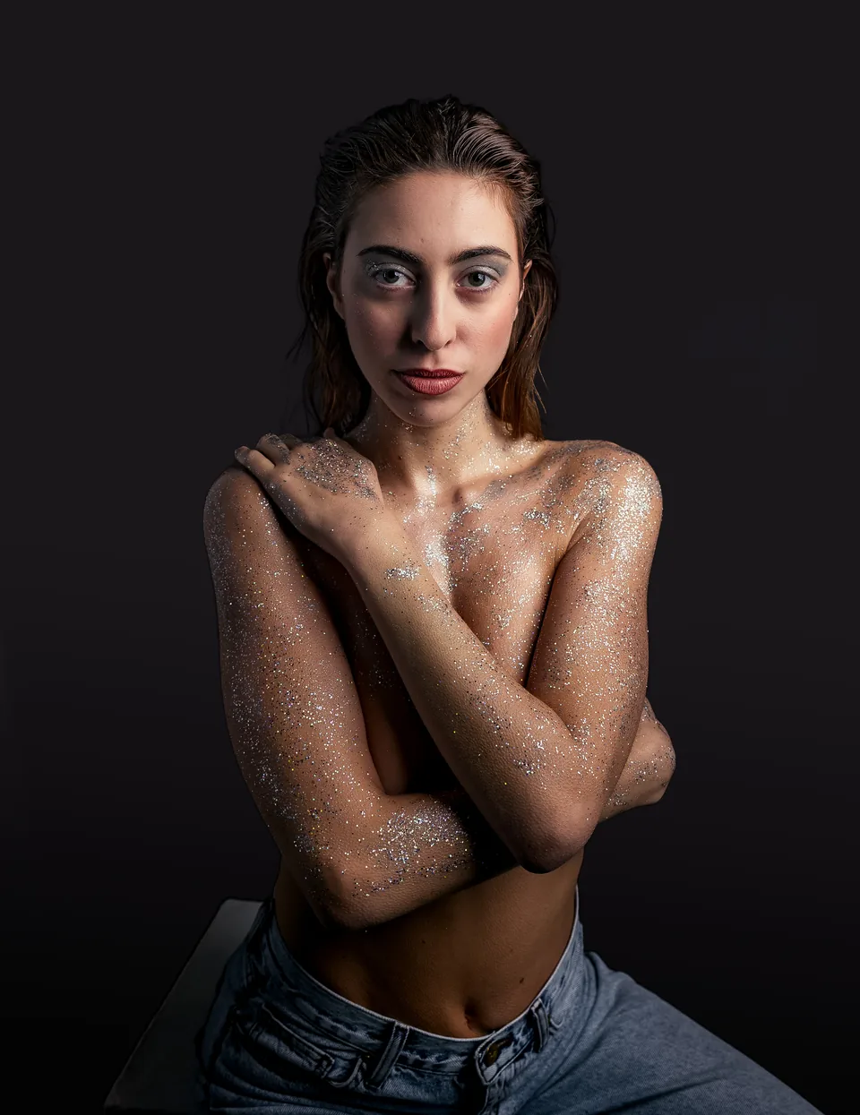 Colour editorial portrait of a glitter-covered model against a dark background