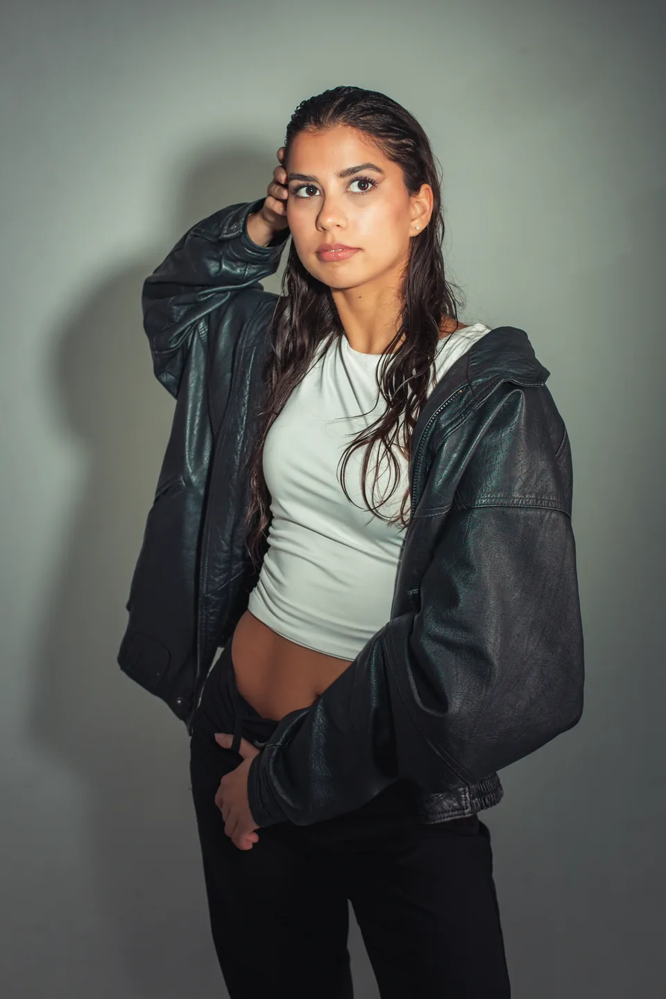 Contemporary model portfolio portrait with wet-look hair and an oversized leather jacket