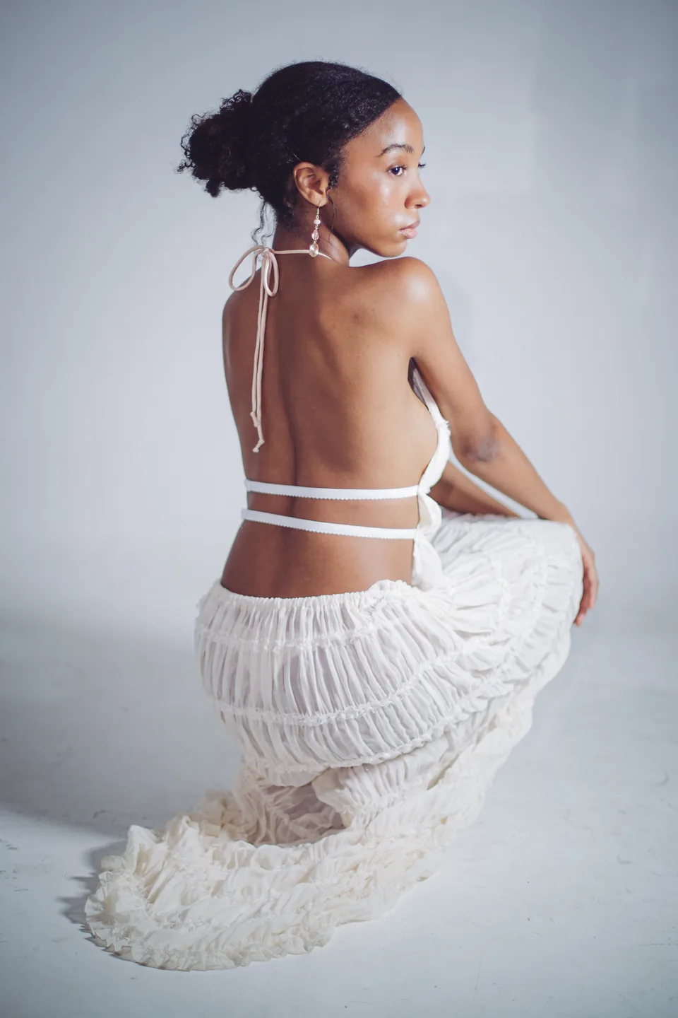Soft editorial portrait of a model in a sculptural white dress