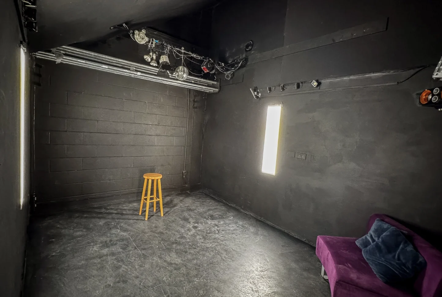 Black photography studio with controlled lighting and a dark textured interior